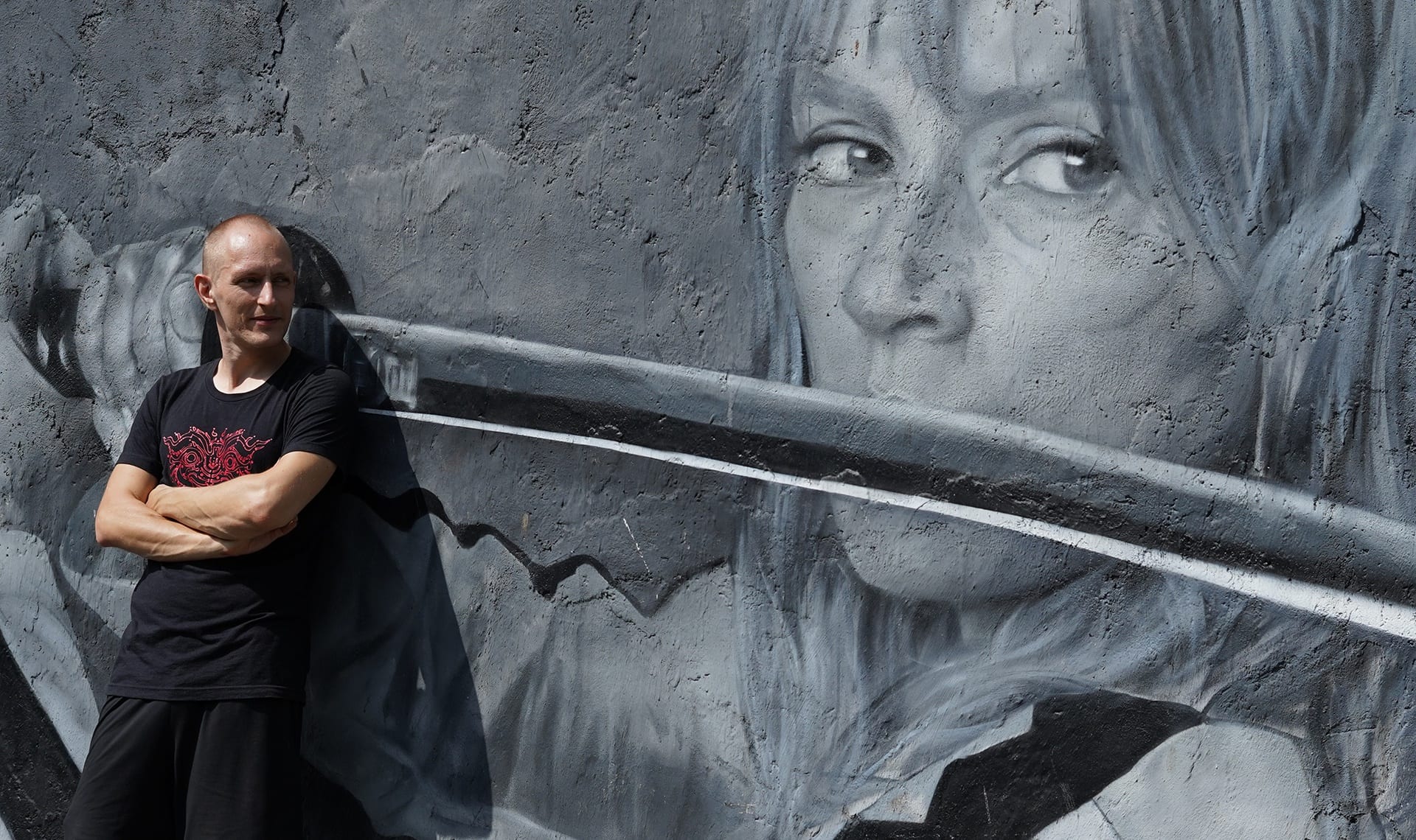 Shane Melaugh, arms crossed, in front of a street mural